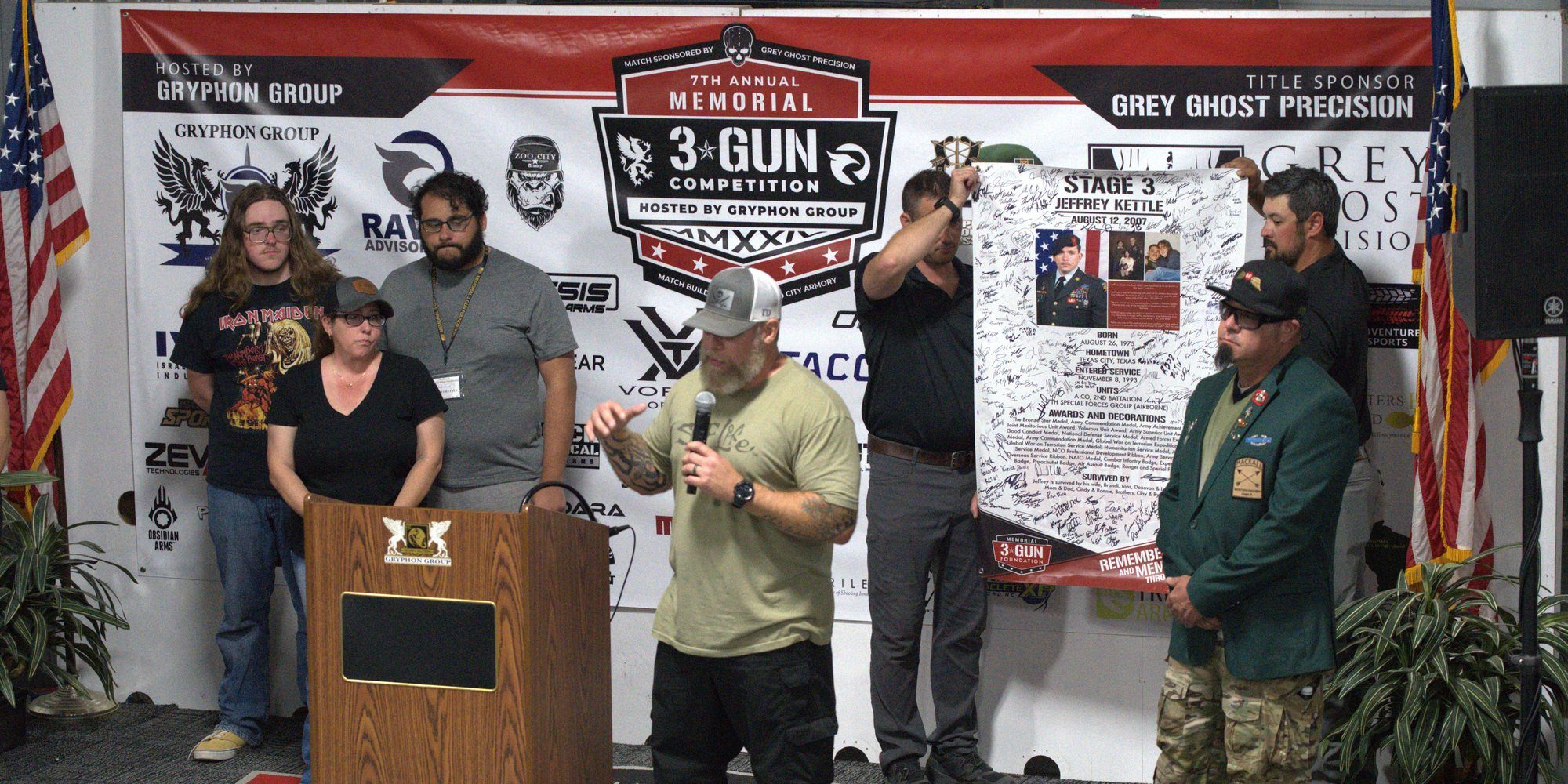 A Gold Star and Surviving family is honored on stage as their hero's signed banner is presented at the 2024 Memorial 3 Gun