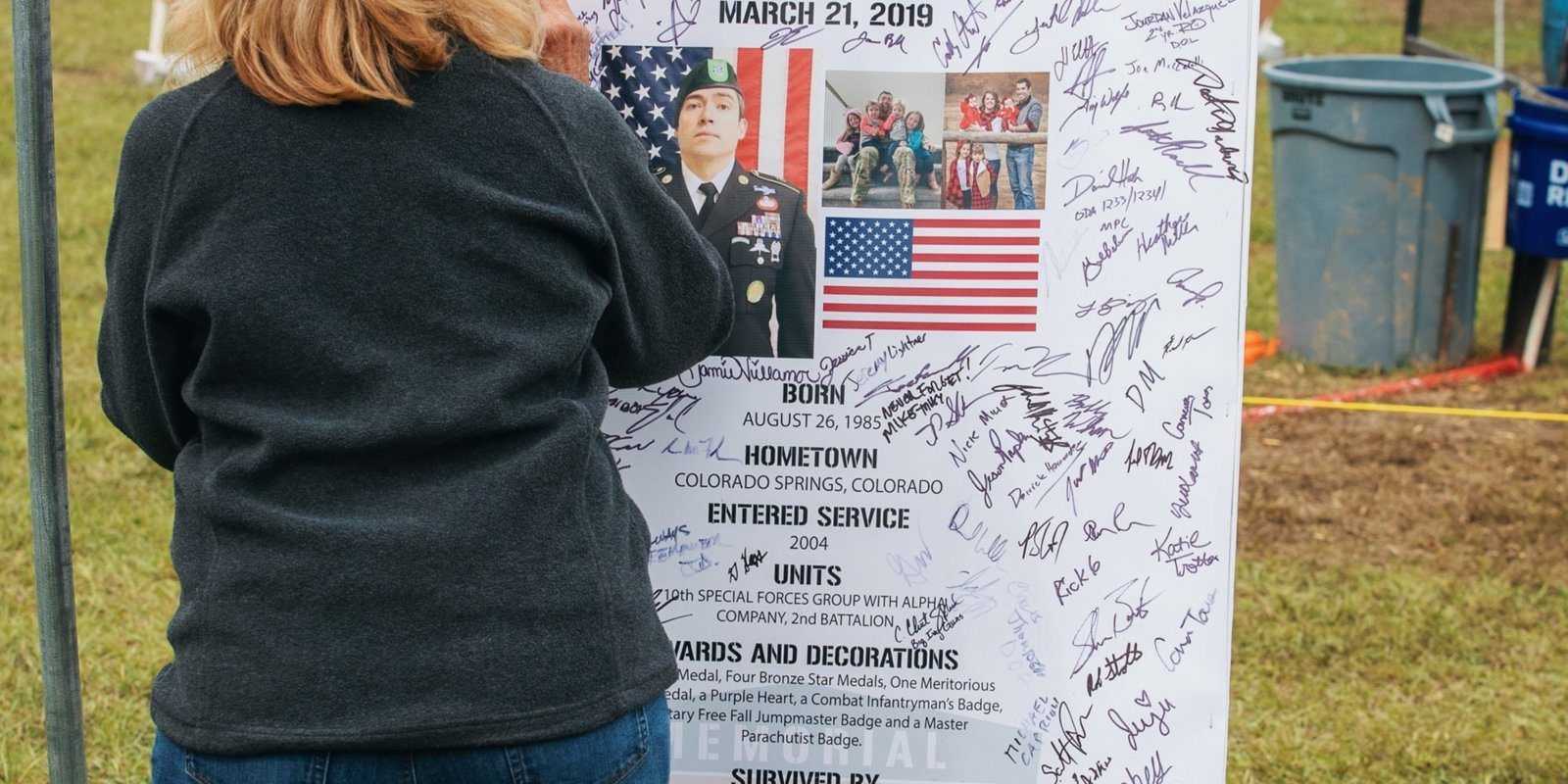 A family member pauses at an honoree's signed stage sign at the 2021 Memorial 3 Gun